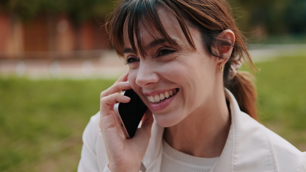 Schedule a dental implant consultation in Scotts Valley, CA Smiling woman speaking on a phone while learning about dental implant treatment in Scotts Valley, CA