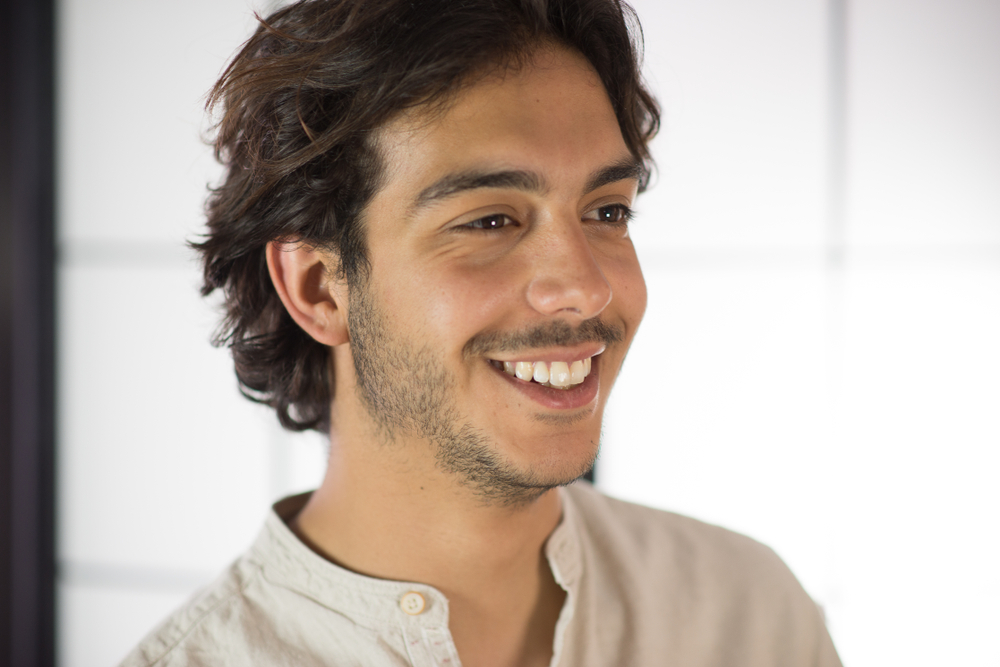 Professional Dental Care Results in Scotts Valley An handsome young man, 20Y, is posing in studio in a smiling pose . White skirt. Retroilluminated booths in the background.
