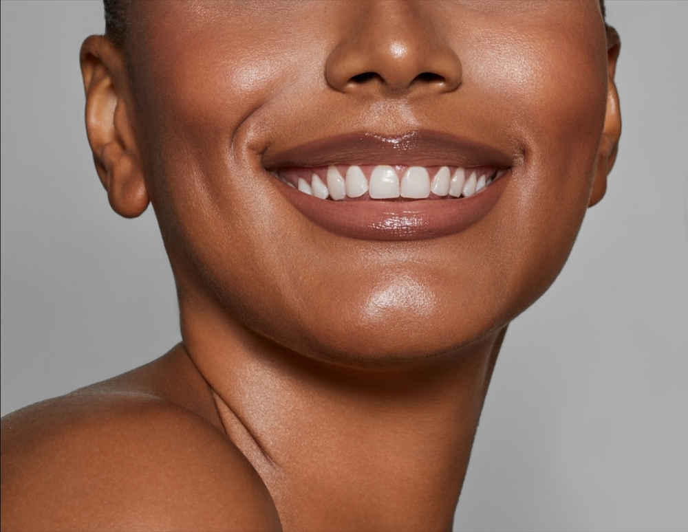 Beautiful young African woman smiling with smooth dark skin – close-up beauty portrait