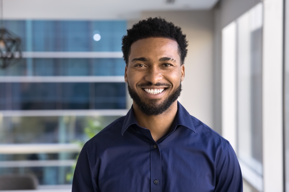 Cosmetic Dentistry for the Santa Cruz Community Cheerful handsome young African American businessman posing for head shot in office, looking at camera with toothy smile. Confident successful Black business leader man, startup manager portrait