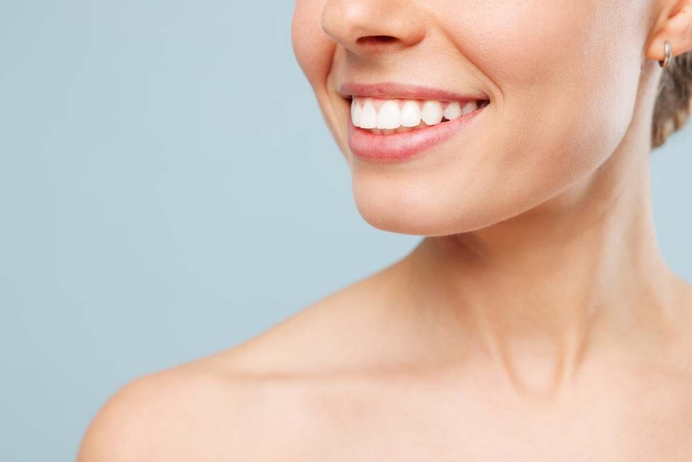Teeth Whitening Results at Mt. Hermon Dental Care, Scotts Valley Close up cropped smiling happy half naked topless young woman 20s with nude make up and toothy smile isolated on plain pastel blue color background. Skin care healthcare cosmetic procedures concept