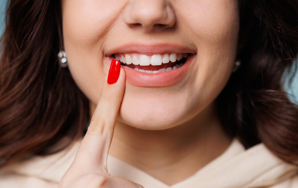 Scotts Valley Dental Patient Happy girl showing toothy smile, pointing finger at healthy white teeth. Clinic patient satisfied with dentist service, enamel cleaning, whitening, dental care, correction. Cropped shot, close up