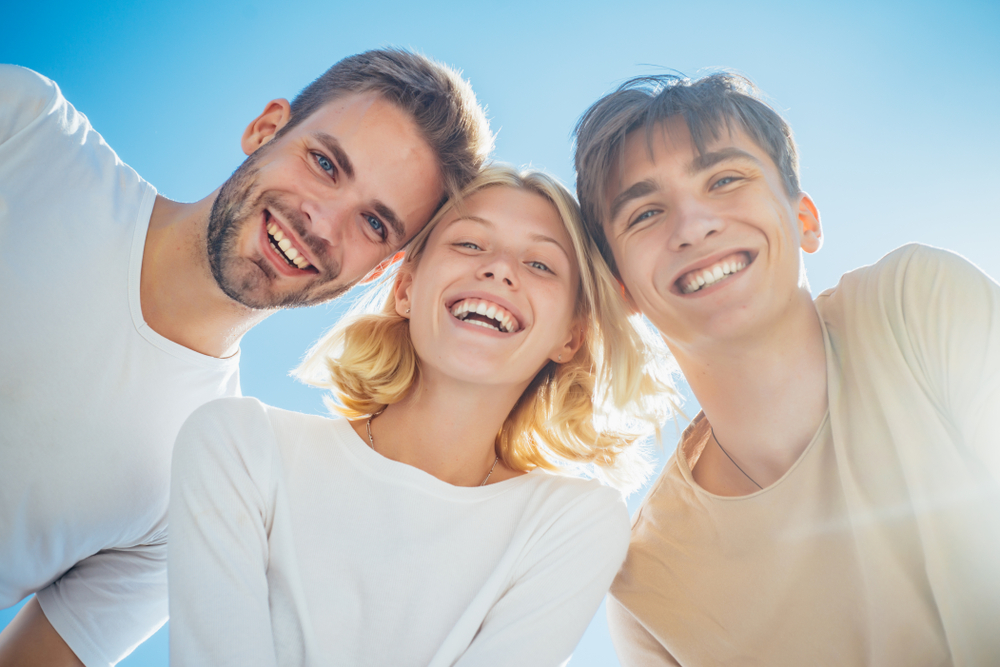 Confident Smiles from Dental Care in Scotts Valley Happy group young people. Cheerful smiling happy best friends walking outdoor together and having great time. Sweet memories about summer holidays. Leisure activity and friendship concept