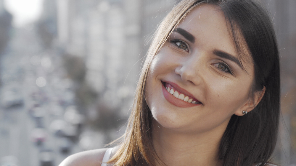 Teeth Whitening Results at Mt. Hermon Dental Care, Scotts Valley Lovely young happy woman smiling to the camera with city streets on background