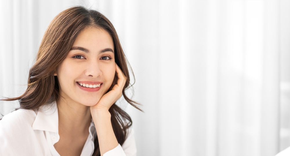 Portrait of smiling cheerful beautiful pretty asian woman clean fresh healthy white skin posing smile in pajamas white clothes.Girl felling relax and enjoy time on the bed at home.asia beauty
