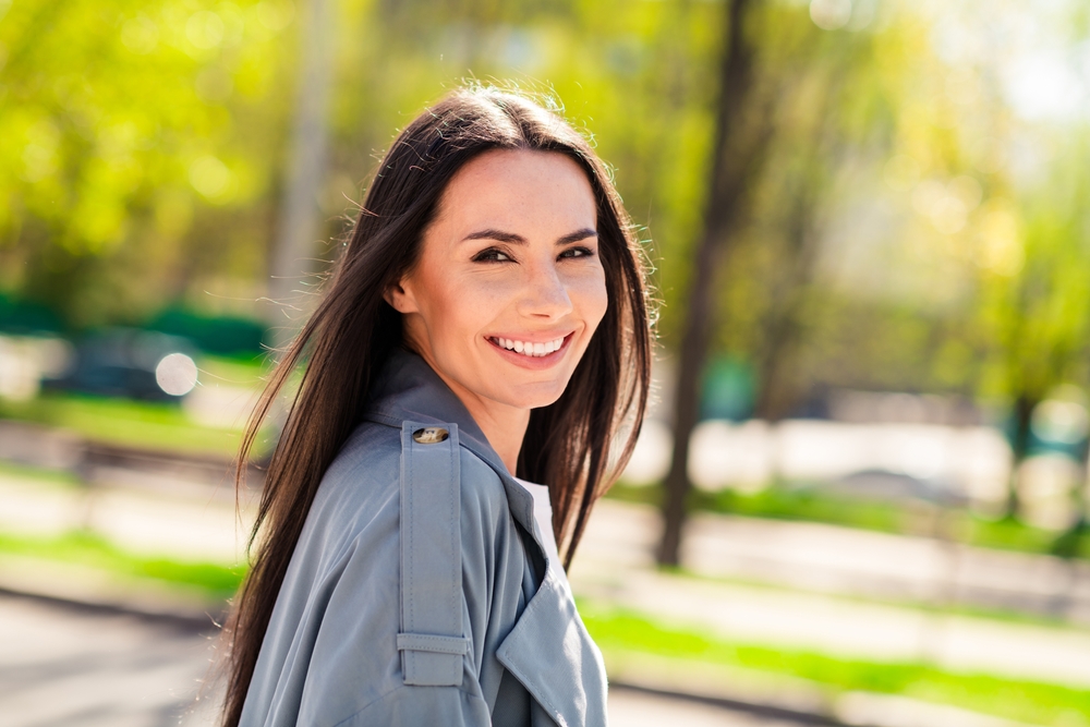 Portrait photo of adorable young smiling glad hispanic attractive lady wearing gray coat walking outdoors relaxed in nature