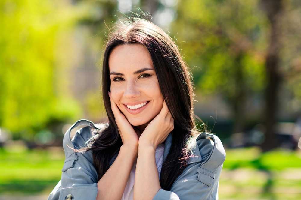Portrait photo of beautiful young smiling latin attractive lady wearing gray coat enjoy outdoors nature sunshine summertime weather