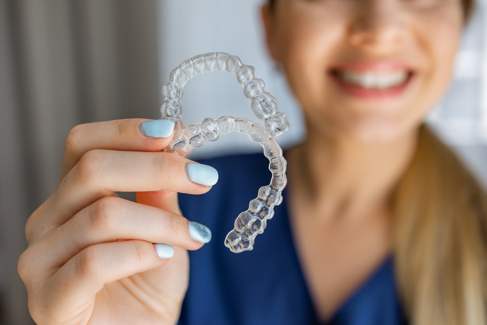 Scotts Valley Dental Patient Professional dental care concept showing a close-up of clear orthodontic aligners held by smiling person, effective teeth correction solutions for achieving confident smile.