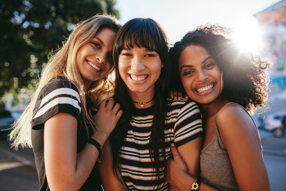 Cosmetic Dentistry for the Santa Cruz Community Three beautiful smiling girl friends standing together. Multi ethnic group of women outdoors in the city looking happy.