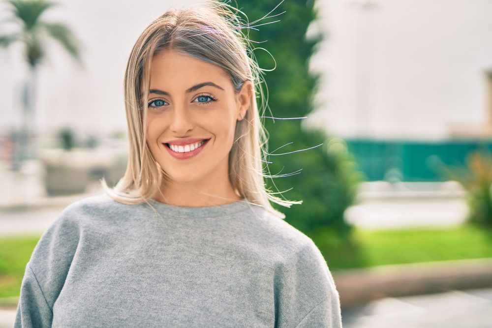 Confident Smiles from Dental Care in Scotts Valley Young blonde girl smiling happy standing at the city.